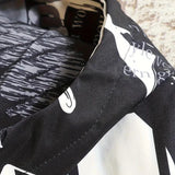 Black and white typographic design shirt featuring newspaper print patterns, short sleeves, and a casual fit.