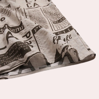 A newspaper print shirt featuring a modern vintage urban fashion design with various newspaper-style patterns and text, resembling currency and banknotes in black and white tones.