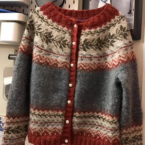 Chunky knit vintage sweater made from handknit wool featuring a white and tartan plaid design, displayed on a clothes hanger highlighting the sleeves and collar.