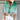 Woman wearing a green V-neck blouse with a beach scene design, paired with a tassel necklace, in size 3XL.