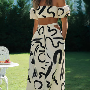 Off-shoulder black and white two-piece dress styled with short sleeves, showcasing a chic summer fashion look, with a background of a window and lush greenery.