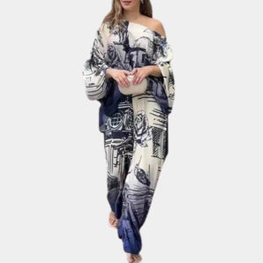 Off-shoulder bohemian wide-leg jumpsuit in navy and white, featuring a relaxed beachwear design with a blue ocean color theme. The jumpsuit highlights shoulder and neck details with flowing sleeves, suitable for a laid-back summer look.