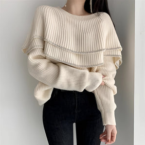 Off-shoulder ivory ribbed sweater with intricate beaded details, highlighting the shoulder and neckline area.