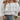 White off-shoulder ruffle blouse with a bow-tie front, featuring loose sleeves and a flowy design suitable for casual and fashion-forward looks in size XL.