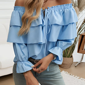 
A stylish off-shoulder ruffle blouse in blue with a bow-tie front design, featuring a loose fit and long sleeves, perfect for adding a fashionable touch to any outfit.