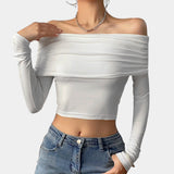 A woman wearing an off-shoulder white long sleeve crop top, showcasing a stylish fall fashion look. The top fits snugly around the waist, accentuating her shoulders and arms.