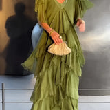 Olive green bohemian tiered midi dress in a vintage chic style, featuring a flowing design with a defined waist and long sleeves, modeled by a fashion model.
