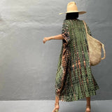 Olive green boho kimono dress worn by a woman at the beach, featuring a lightweight one-piece design perfect for summer, with a sun hat complementing the outfit.