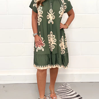 Olive green floral bohemian dress in size 5XL featuring a casual chic style suitable for summer festivals. The one-piece garment has a flattering day dress design with a defined waist, short sleeves, and a modest neckline.