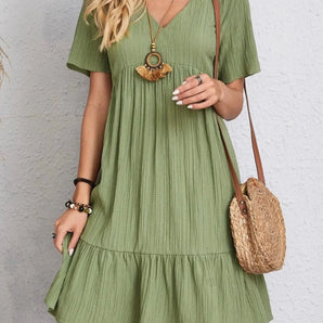Olive green flowy mini dress with short sleeves and a ruffle hem, designed in a boho chic style. The dress features a flattering waistline and is available in size 2XL.