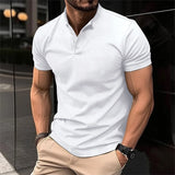 Olive green men's fitted polo shirt with short sleeves, worn by a model. The shirt is styled casually smart and is available in size 2XL. The model is wearing eyewear and the polo shirt features a classic collar and button placket.