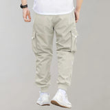 Olive green men's tapered cargo pants featuring a lightweight design with utility pockets, showcasing a fashionable fit around the waist and thighs, styled with casual sportswear.