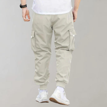 Olive green men's tapered cargo pants featuring a lightweight design with utility pockets, showcasing a fashionable fit around the waist and thighs, styled with casual sportswear.