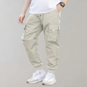 Olive green men's tapered cargo pants with multiple pockets, showcasing a lightweight and stylish utility design suitable for fashion and active wear.