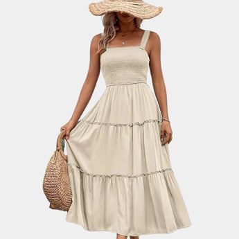 Olive green smocked bodice strappy midi dress featuring a fitted bodice with a cinched waist, displayed on a mannequin styled with an apricot hat.