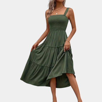 Olive green smocked bodice strappy midi dress displayed on a mannequin, featuring a fitted waist and flowing skirt that falls to mid-calf length, showcasing its elegant and casual daywear style.
