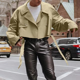 Olive green tie-waist cropped blazer worn by a woman, styled for an office look, featuring tailored outerwear paired with a dress shirt, with emphasis on the blazer's design and color.