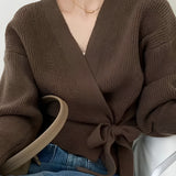 Olive green women's V-neck wrap sweater with long sleeves, styled casually with jeans, showcasing a chic autumn fashion look.