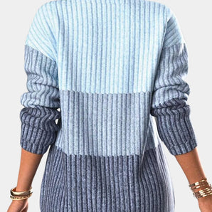 A woman wearing an ombre gradient knit sweater with blue stripes, posing with her shoulder slightly turned. The sweater is part of women's fashion knitwear, providing a casual yet chic appearance.