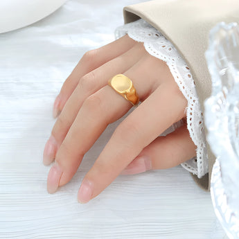 A 9mm 18K gold plated lightweight ring on a person's finger, showcasing minimalistic design, worn with a dress.