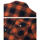 Men's orange plaid flannel shirt made of cotton with a tartan pattern and pockets, displayed against a rustic wooden background.