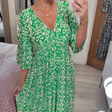 Orange and white geometric patterned V-neck summer dress with a cinched waist, shown in a green color and size 5XL. The dress features short sleeves and a comfortable fit, ideal for warm weather.