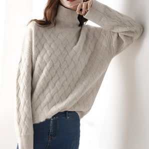 Oversized beige cable knit turtleneck sweater featuring a cozy and textured winter design with long sleeves and a high collar.