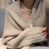 Oversized beige chunky knit women's cardigan featuring long sleeves and a cozy collar, perfect for winter fashion.