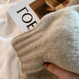 Oversized beige chunky knit women's cardigan featuring textured sleeves, shown worn by a model.