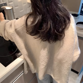 Oversized beige chunky knit women's cardigan worn by a person with long hair, featuring long sleeves and a cozy design, ideal for winter fashion.