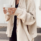 
A woman wearing an oversized beige corduroy jacket, styled for casual fall fashion. The jacket features long sleeves and a relaxed fit, suitable for layering over various outfits. The woman is posed with one arm slightly bent, showcasing the jacket's soft texture and comfortable design. She pairs the jacket with neutral-toned clothing and shoes, emphasizing the versatile and chic nature of the outfit.
