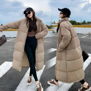 Oversized beige puffer coat for women, showcasing a trendy long winter jacket design in Cachi color, size 3XL, with a person wearing sunglasses standing outdoors under a cloudy sky.