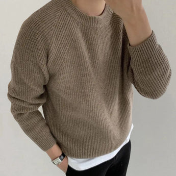 
An oversized black ribbed knit sweater for men in a relaxed fit crewneck style, shown in a khaki color, size XL, with a focus on the upper body including shoulders and arms.