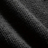 A men's oversized black ribbed knit sweater with a relaxed fit and crewneck design displayed against a dark, textured background.
