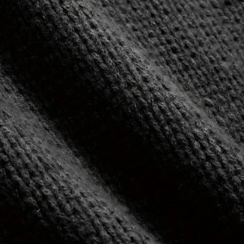 A men's oversized black ribbed knit sweater with a relaxed fit and crewneck design displayed against a dark, textured background.