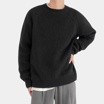 Men's oversized black ribbed knit sweater with a relaxed fit, featuring a crewneck design, long sleeves, and textured fabric.