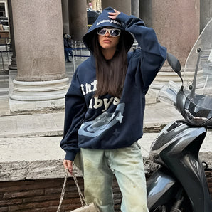Oversized blue camouflage hoodie featuring a streetwear fashion style, worn by a model with sunglasses.