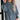 Oversized blue corduroy pullover women's long sleeve sweater worn by a smiling woman with long hair, showcasing the shoulder and arm details against a white background.