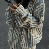 Oversized blue stripe knit sweater featuring long sleeves, shown on a woman wearing sunglasses and holding a mobile phone, capturing a casual autumn fashion style.