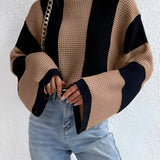 Oversized chunky knit sweater in black and tan stripes, featuring a relaxed fit with long sleeves and a round neckline, ideal for autumn fashion. The sweater is shown in a khaki color and size large, perfect for a cozy and stylish look.