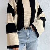 Oversized chunky knit sweater in black and tan stripes, featuring a loose fit design with a round neckline and long sleeves. The sweater is styled for autumn fashion, shown in apricot color in a size large.