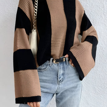 Oversized chunky black and tan striped knit sweater featuring long sleeves, perfect for autumn fashion. The sweater is modeled with jeans, showcasing a cozy and stylish look suitable for cooler weather.
