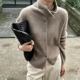 Oversized chunky knit women's brown wool turtleneck sweater in camel color, size XL, featuring a thick collar and long sleeves draped over a seated model, with a subtle pattern and cozy texture.
