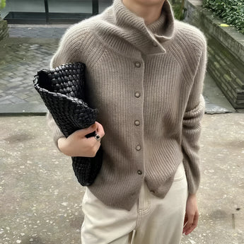 Oversized chunky knit women's brown wool turtleneck sweater in camel color, size XL, featuring a thick collar and long sleeves draped over a seated model, with a subtle pattern and cozy texture.
