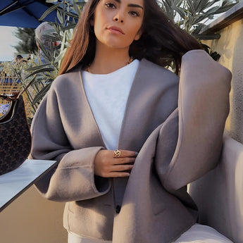 Oversized gray blazer paired with a cropped top and trousers, showcasing a chic streetwear outfit. The blazer features a relaxed fit with prominent sleeves and a notched collar, complementing the fashionable and comfortable ensemble.