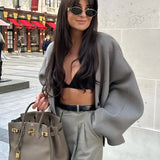Oversized gray blazer paired with a cropped top and trousers, styled for a chic streetwear look, with a focus on fashion-forward details.