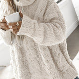 Woman wearing an oversized gray chunky knit turtleneck sweater with cable design, showcasing the pullover style and long sleeves.