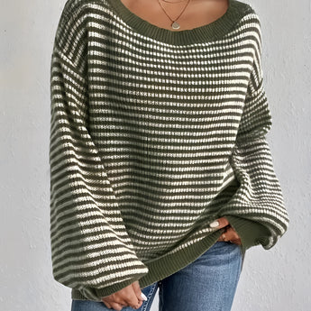 Oversized green striped knit sweater with a cozy boat neck pullover style, worn by a person visible from the shoulders down, paired with jeans.