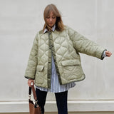 Woman wearing an oversized green quilted puffer jacket with a high collar and long sleeves, suitable for casual autumn wear.