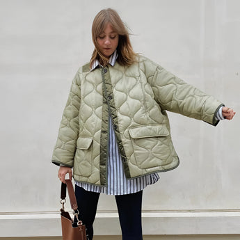 Woman wearing an oversized green quilted puffer jacket with a high collar and long sleeves, suitable for casual autumn wear.